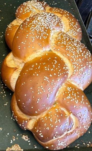 A braided sesame challah loaf fresh from the oven
